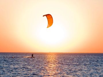 Sunset image of a kitesurfer on the horizon