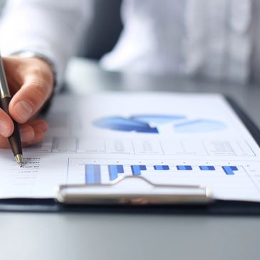 Image of a person holding a pen looking at a document with bar and pie charts