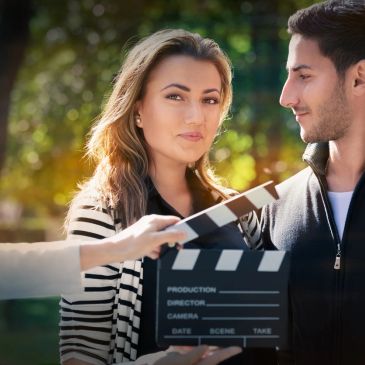 Actors prepare for a scene with a clapperboard on set outdoors.