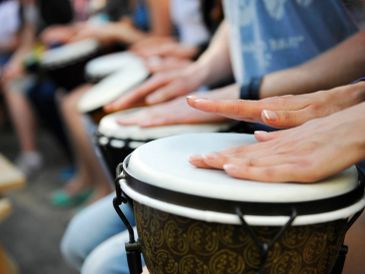 Close-up of hands playing djembe drums in a group setting.