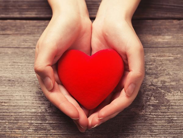 A pair of hands holding a red heart