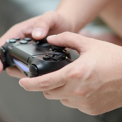Hands holding and playing with a black gaming controller.