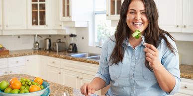 Woman sitting in the kitchen eating healthy food