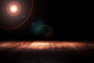 Wooden floor lit by a bright light in darkness.