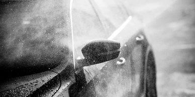 Black car side mirror with rain or mist.