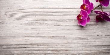 Purple orchids on a textured wooden surface.