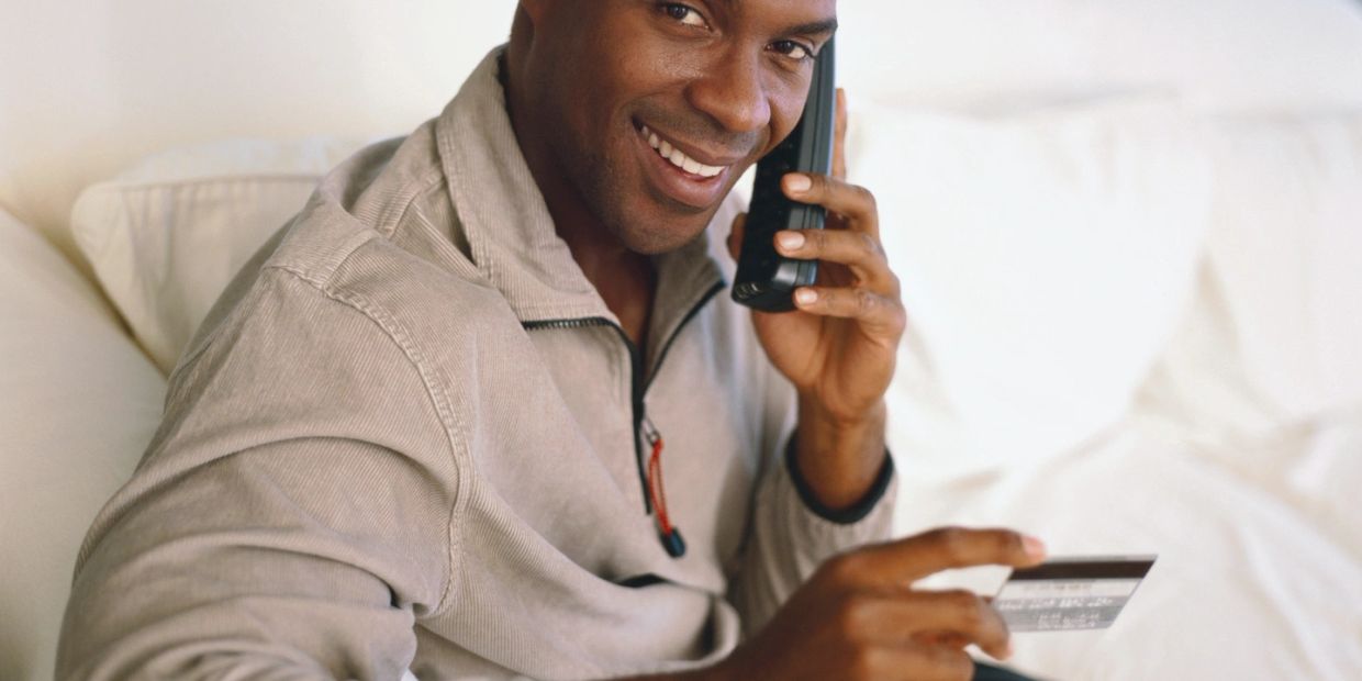 Man on phone holding credit card and smiling.