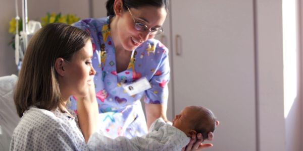nurse giving mother the newborn