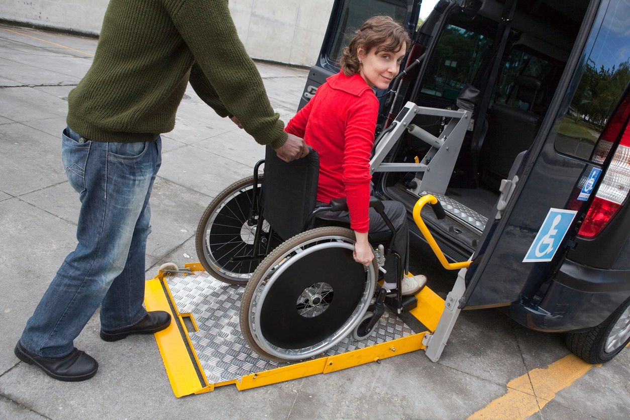 A lady in a wheelchair assisted by a support worker into a accessible van.