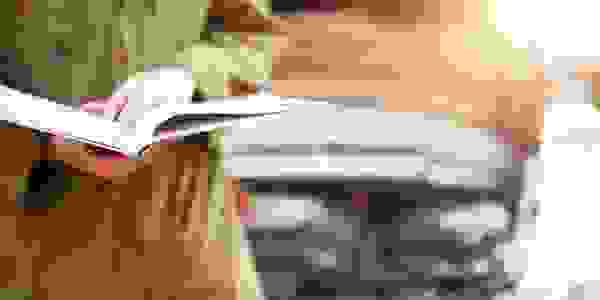 Mechanic holding a book open with a vehicle in the background.