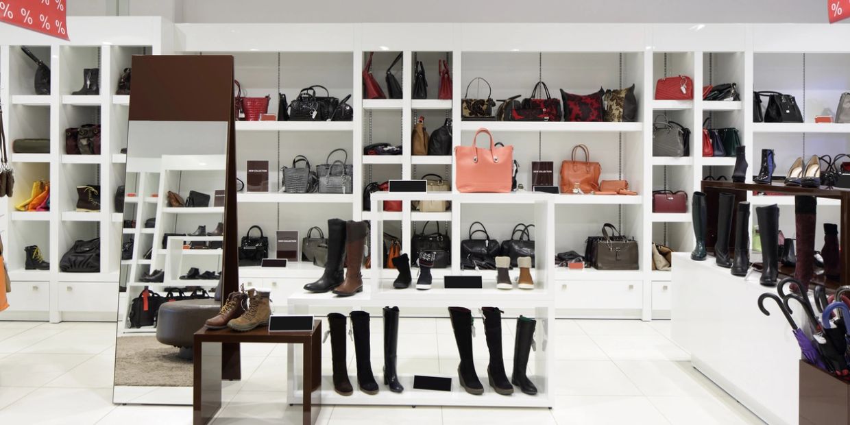 Modern store interior showcasing boots, handbags, and accessories with a large mirror.