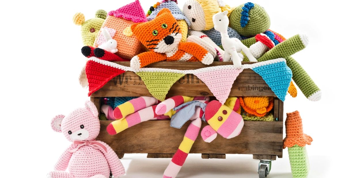A wooden crate filled with colorful crocheted and knitted stuffed toys.