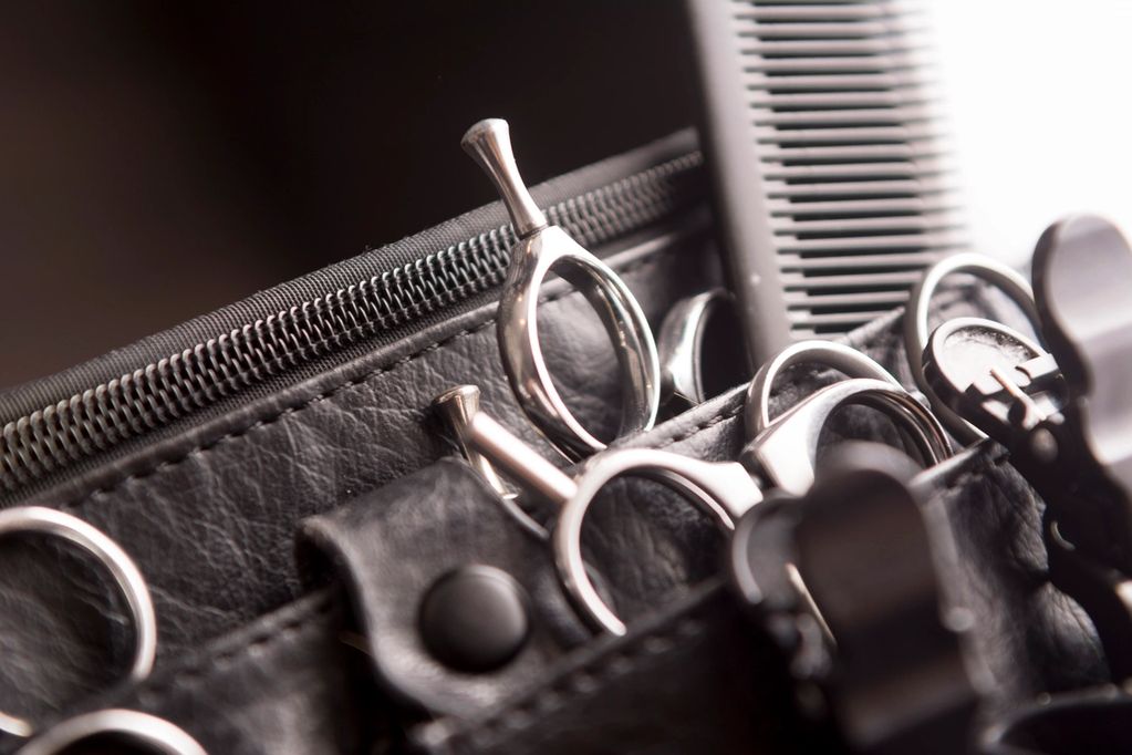 Close-up of hairdressing scissors and a comb in a leather case.