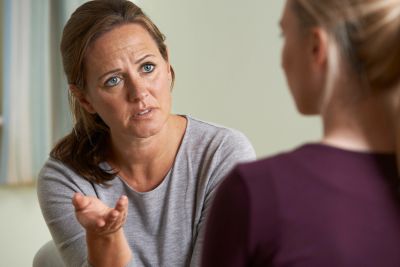 A woman attentively listens and gestures while talking to another person.