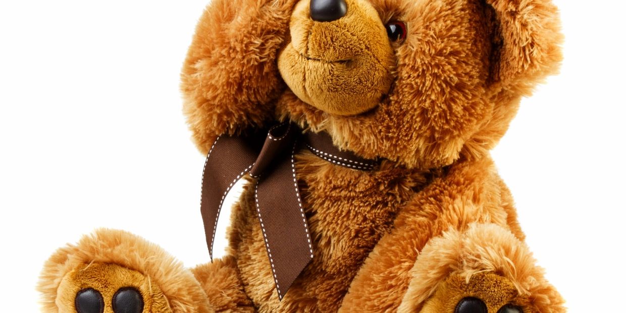 A cuddly brown teddy bear with a dark brown ribbon.