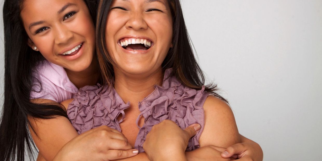 Two women sharing a joyful hug and laughter together.