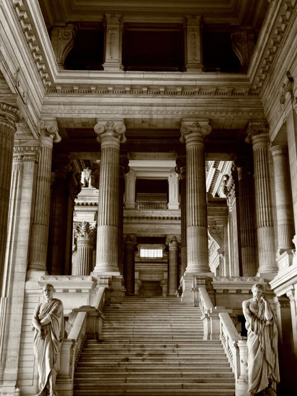 Grand marble staircase with statues and tall columns.