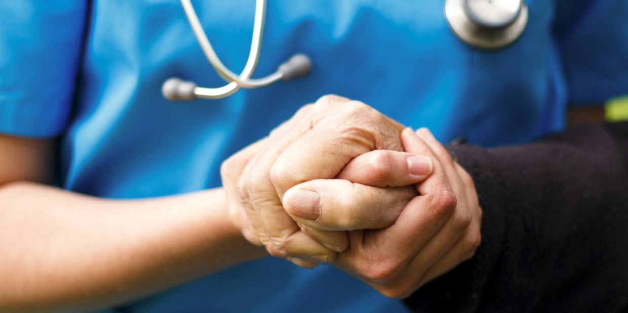 A nurse holding the hand of a patient supporting them 
