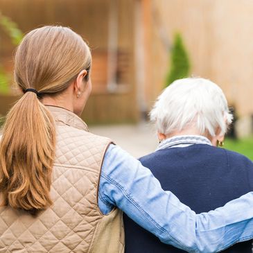 female caregiver (HHA) assisting a elderly man to walk outside