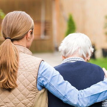 A woman holding an elder person ealking