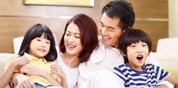 Happy family of four smiling together on a couch.