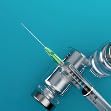 Close-up of a syringe and vaccine vials on a blue background.
