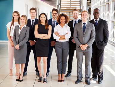 Diverse professional team posing confidently in a modern office hallway.