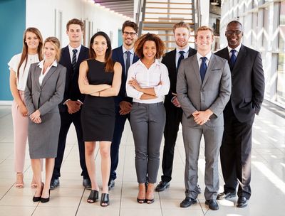A diverse group of professionals posing confidently in an office corridor.