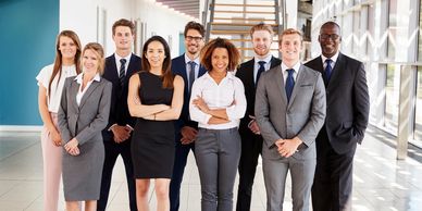 A diverse group of professionals posing confidently in a modern office corridor.