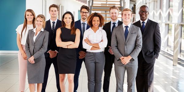 A diverse group of professionals standing confidently in an office hallway.