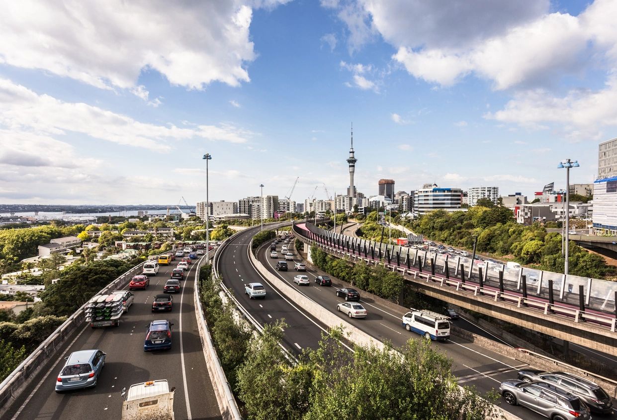 A bright day as an overview of traffic shows cars commuting on the highway leading to three different destinations on a city's infrastructure.