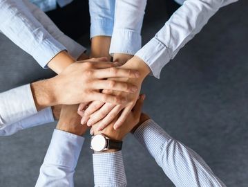 Multiple hands stacked together symbolizing teamwork and unity.