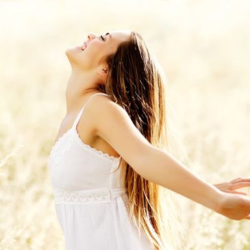 Lady in a white dress with arms open behind her looks happy and free. 