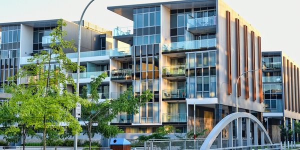 Modern apartment building with glass balconies and greenery.