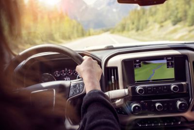 Person driving a car on a scenic road with GPS navigation on.