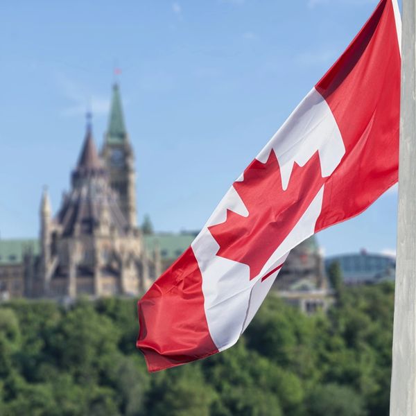 Canadian flag waving in front of a historic building.