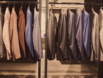 Neatly arranged men's jackets and blazers hanging on a rack.