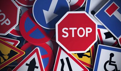 Stop sign laying down on a plie of other street signs