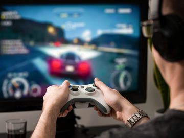 Person playing a racing video game on a console with a controller.