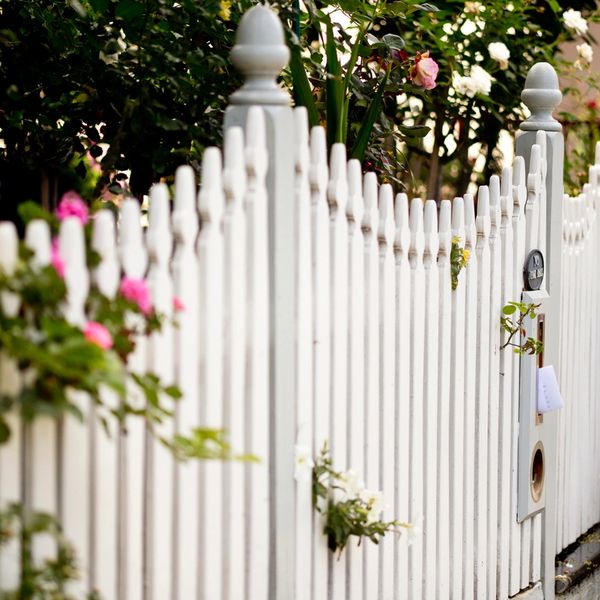 White picket fence adorned with blooming flowers in a garden.
