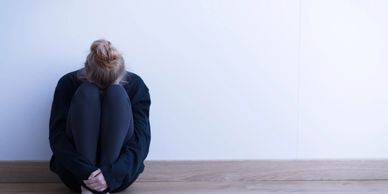 A sad woman sitting on the floor with head down 