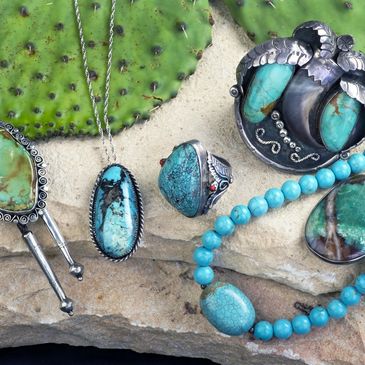 Turquoise jewelry set displayed on a stone surface with cactus background.
