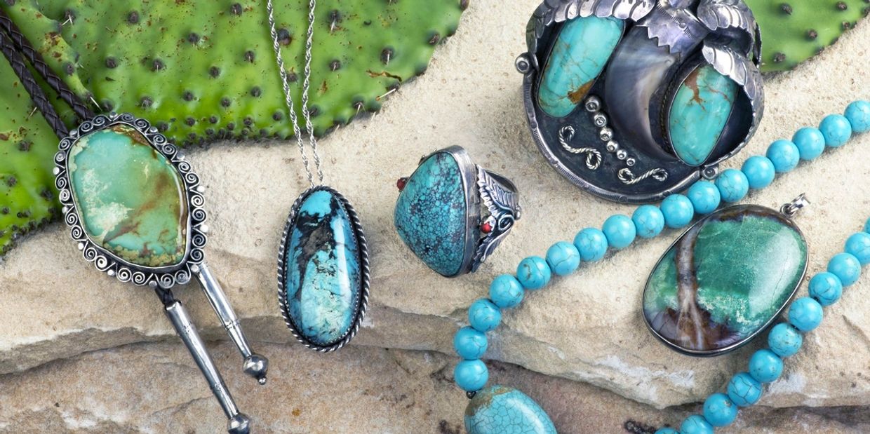 Turquoise jewelry displayed on a stone surface with cactus background.
