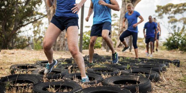 People exercising by stepping through tires outdoors as a group.