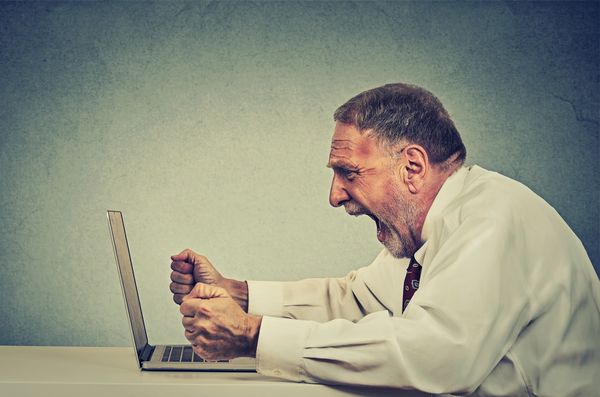 Frustrated man yelling at laptop.
