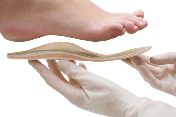 A foot being measured or fitted with a supportive orthotic insole.