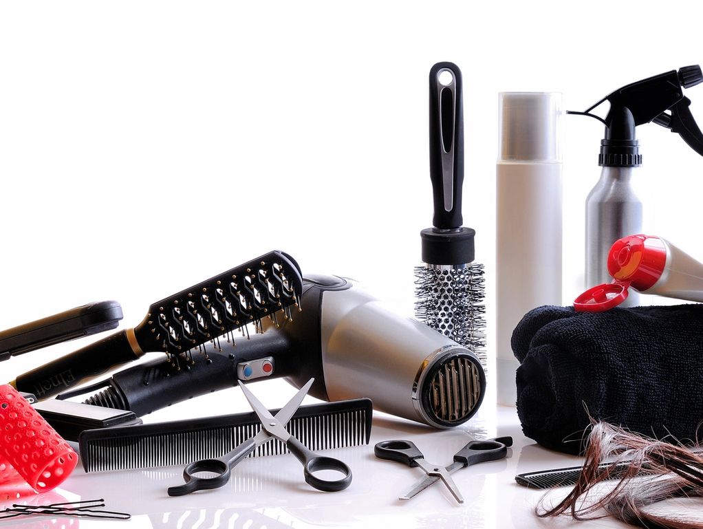 Hair styling tools and products arranged on a white surface.