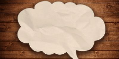 Blank speech bubble on wooden wall background.