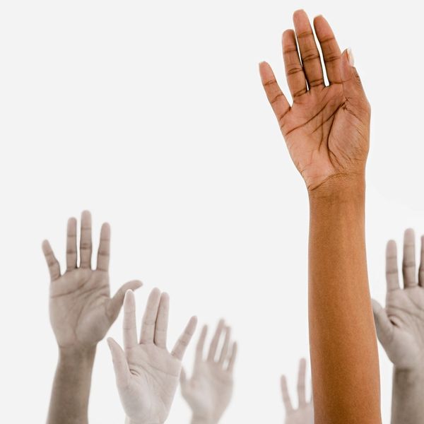 Raised hands with one prominently darker hand standing out.