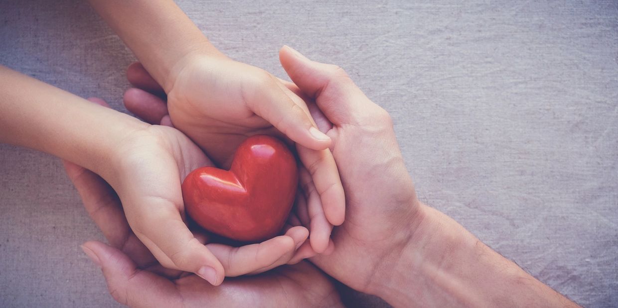 Two people holding hands and a red heart